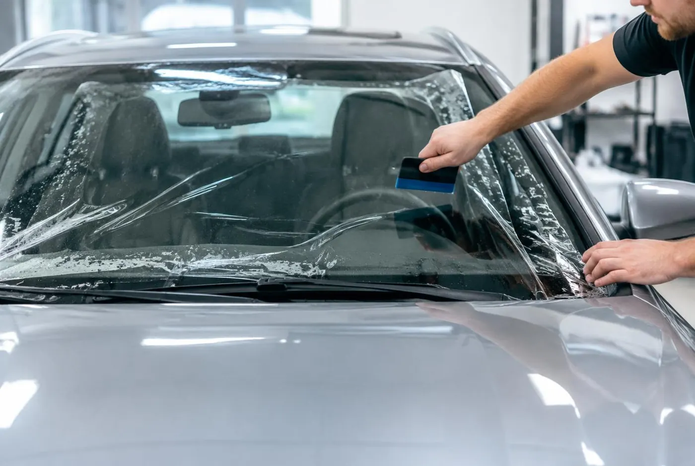 Clear protective film being installed on a car windshield